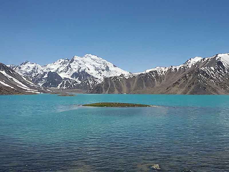 Blue lake of Zajorkul in the Pamir Mountains with small island and snowy mountains in background