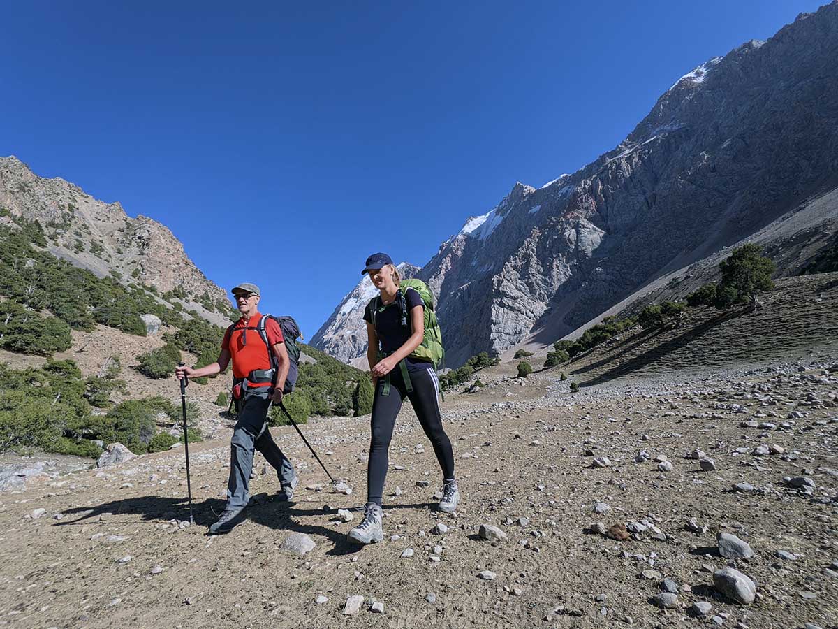 Two hikers trekking with backpacks through the Archamaidan valley in the Fann Mountains
