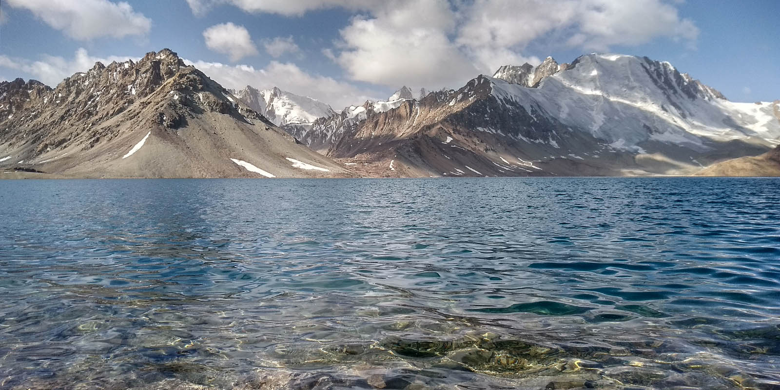 View from very near to water level of Chapdarkul with snowy mountains in the background