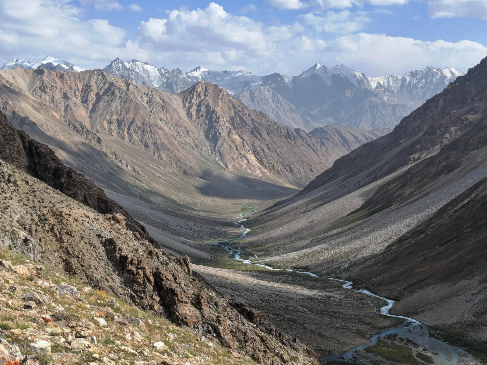 View from above over the Andaravadzh Valley with a braiding river and jagged mountain ranges in the background