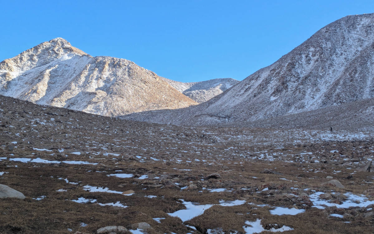 Hiker walking across a snowy scree slopes towards Bel Ayrik Pass