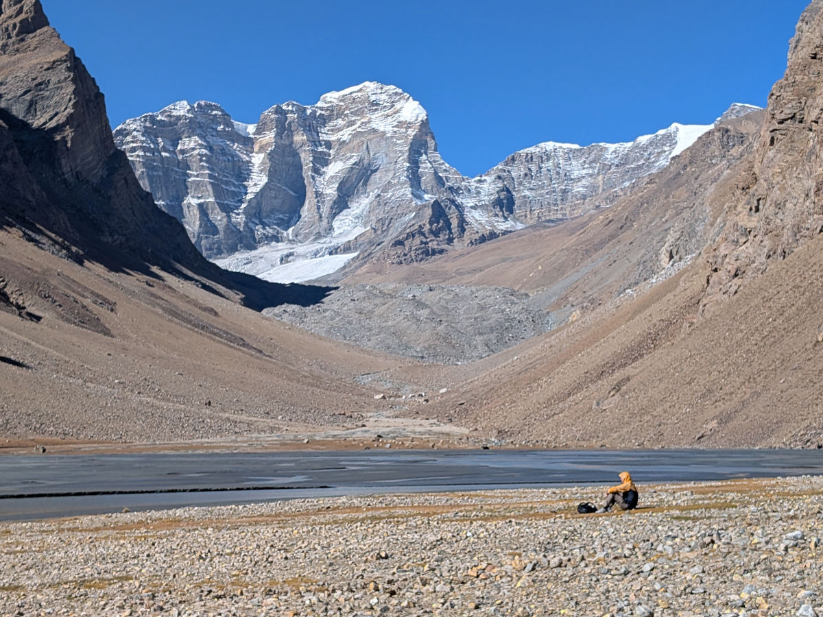 Hiker sitting on the bank of a river with Engels Peak towering in the background