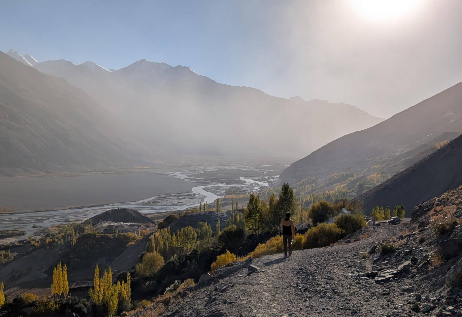 Hiker walking down a trail in the Wakhan Valley as the sun is setting