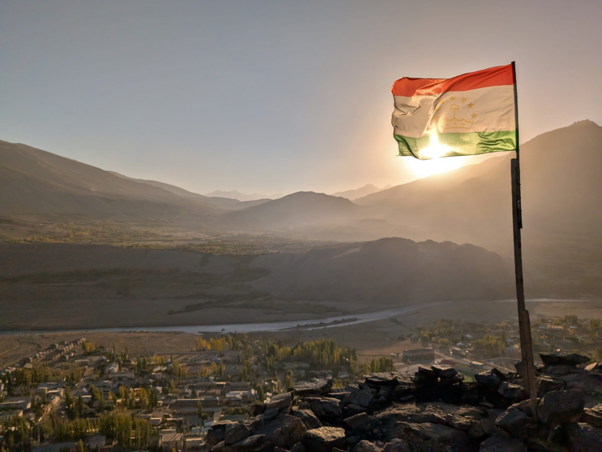 Tajik flag fluttering in the wind with the sun shining through it at Ishkoshim