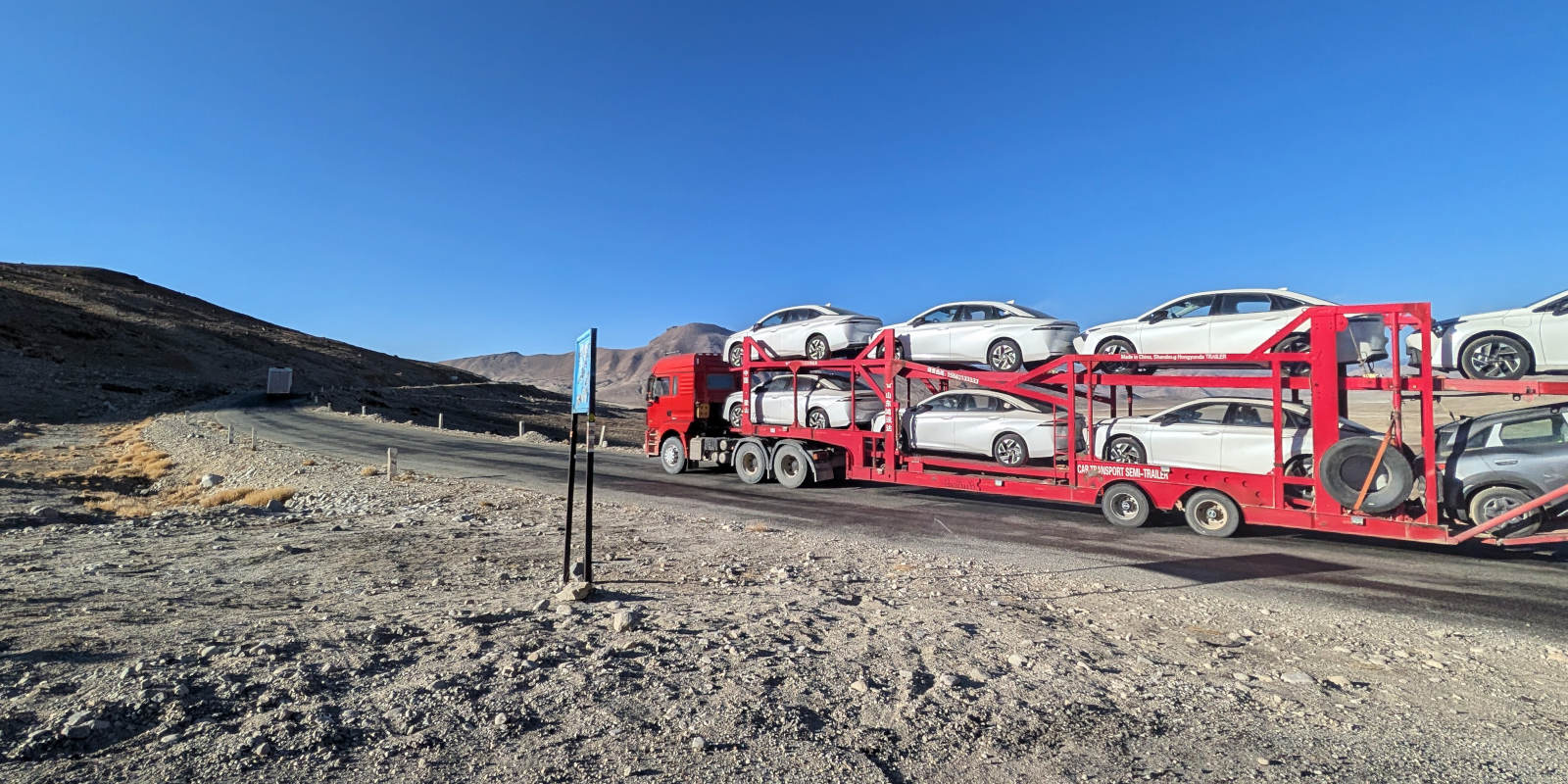 Red truck transporting 8 electrical cars from China (Kashgar) to Dushanbe across the Pamir Highway