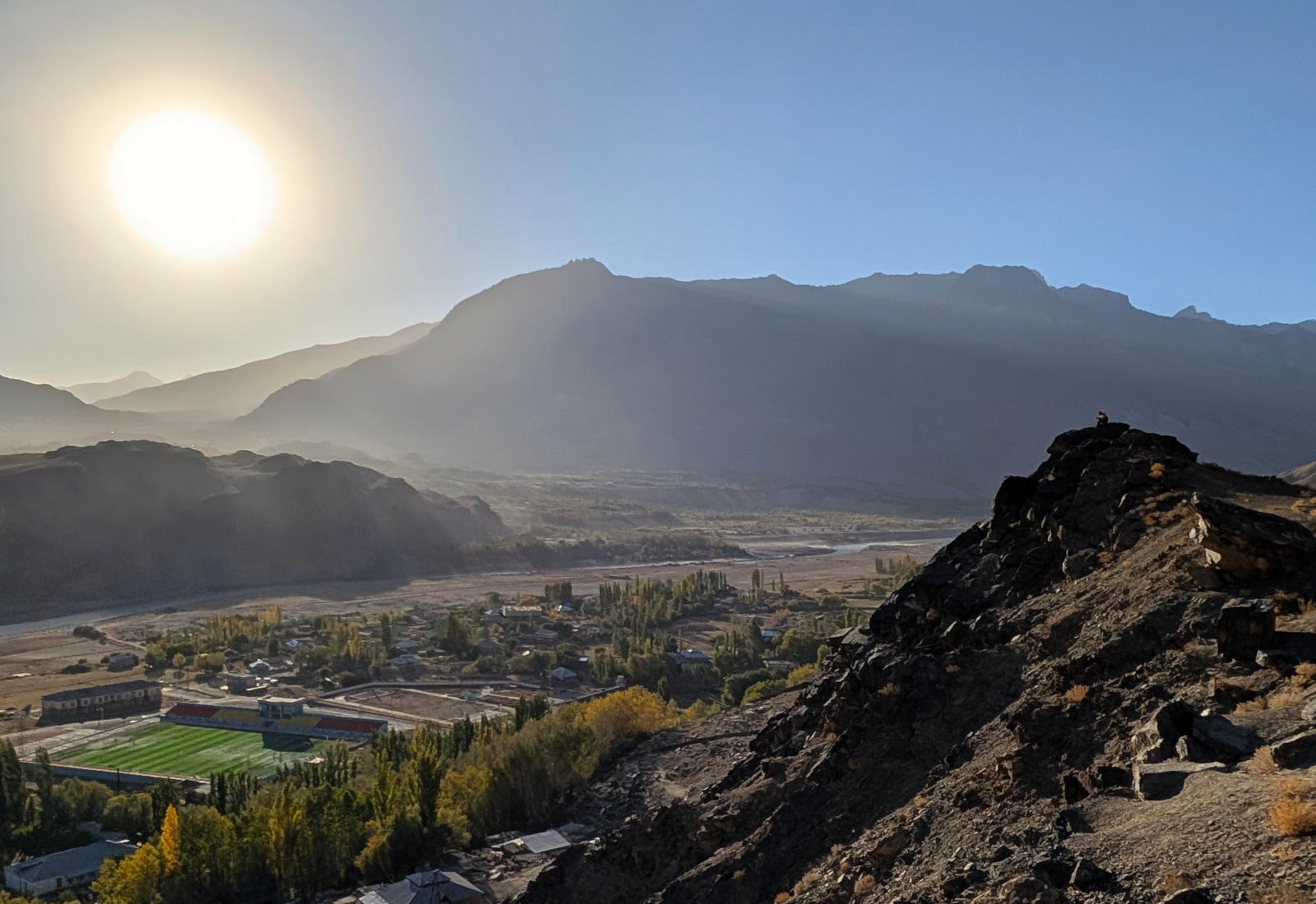 Person sitting on a small peak overlooking the Wakhan Corridor at sunset