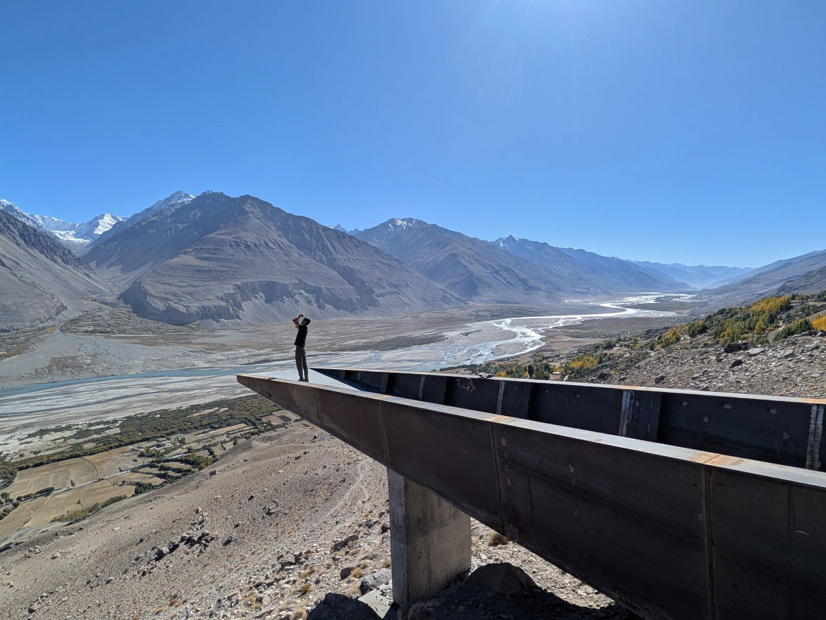 Person standing on the Yamchun Fort bridge viewpoint stretching out over the Panj Valley